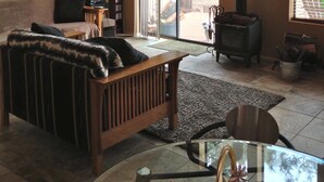 A cozy living room with a wooden ceiling, a fireplace, a sofa, a TV, and large windows. - Sweet Getaway House Close to all the best Arizona has to offer (Parks)