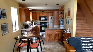 A compact kitchen with wooden cabinets, a dining table with chairs, a built-in stove, and a water dispenser. - Sweet Getaway House Close to all the best Arizona has to offer (Parks)