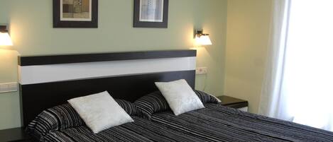 A neatly arranged hotel room with a large bed, two bedside tables, and two wall-mounted lamps.