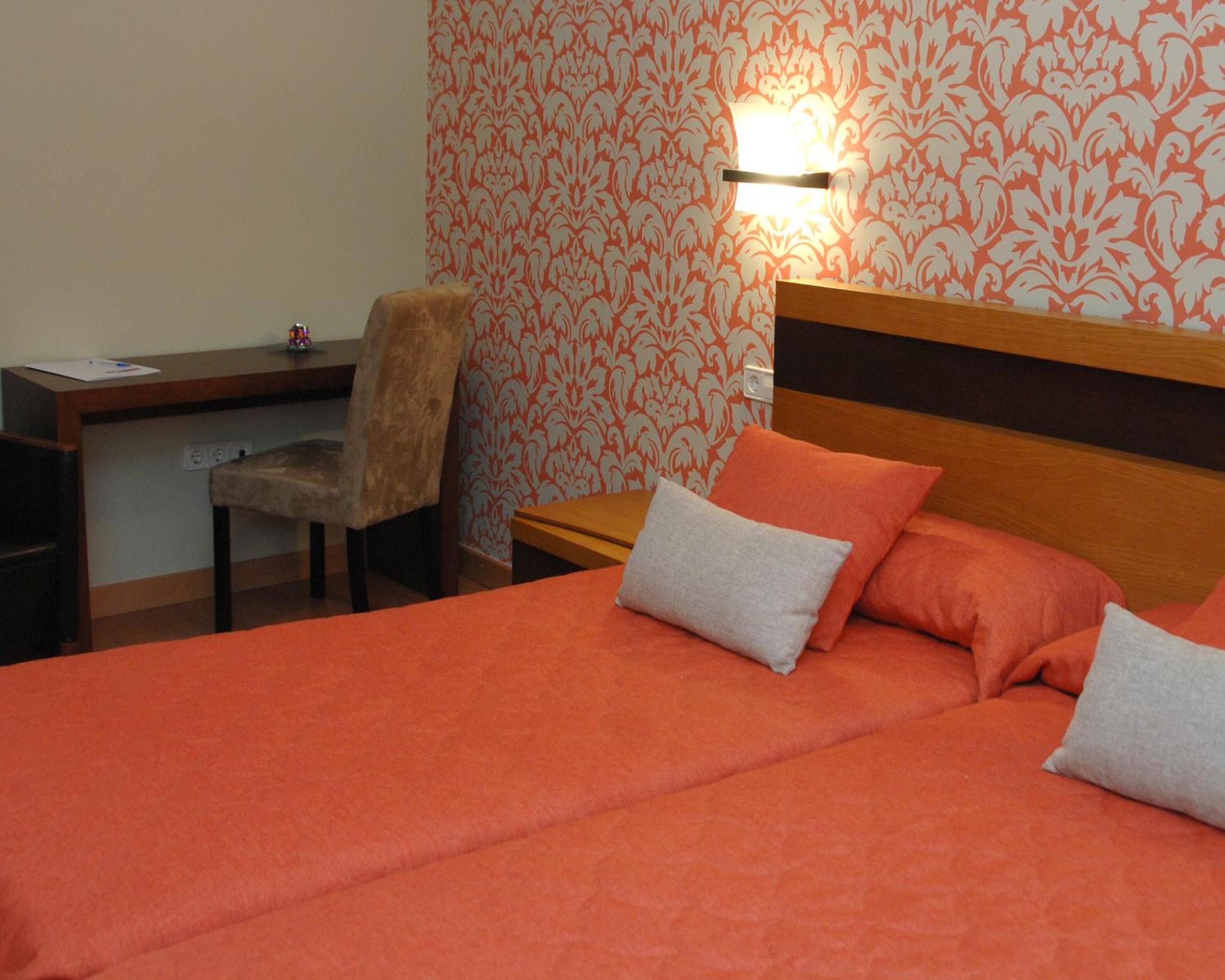 A hotel room with a bed, a desk, and a chair.