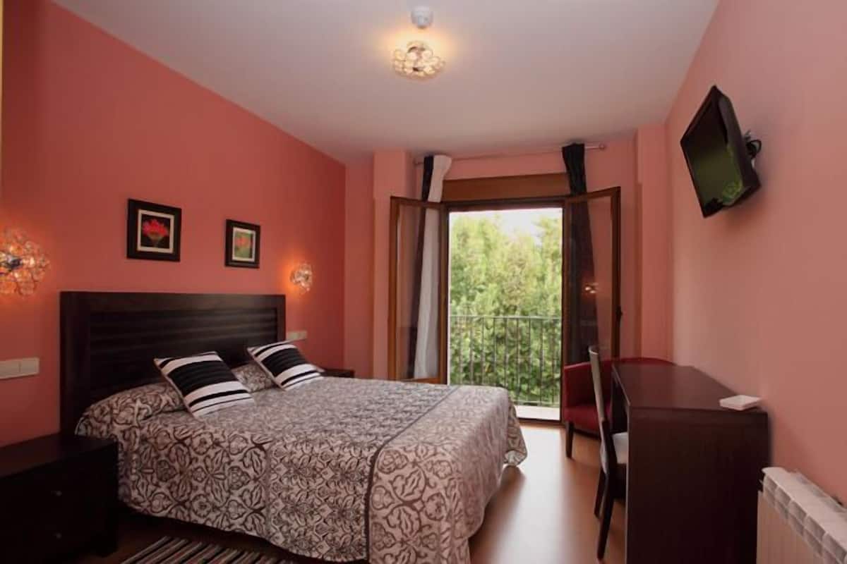 Ein Schlafzimmer mit Bett, Schreibtisch und Fernseher.