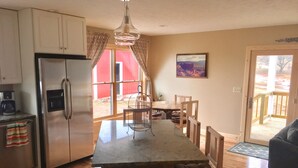 Uma cozinha com ilha central, cadeiras de madeira, geladeira e mesa de jantar.