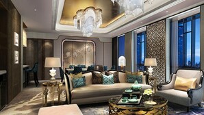 Ein luxuriöses Hotelzimmer mit einer großen Couch, Sesseln, einem Couchtisch und einem Kronleuchter.