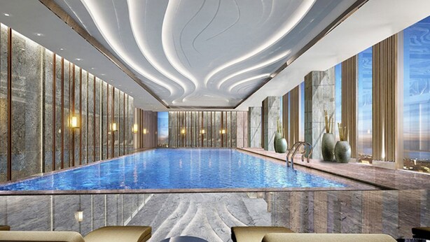 Ein moderner, überdachter Pool mit Marmorboden, einer gewölbten Decke mit integrierter Beleuchtung und großen Fenstern mit Blick ins Freie.