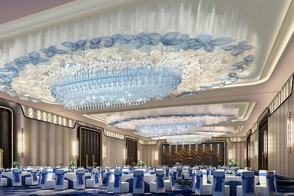 Ein Banketthaus mit runden Tischen, blauen Stühlen und einer großen Chandelier.