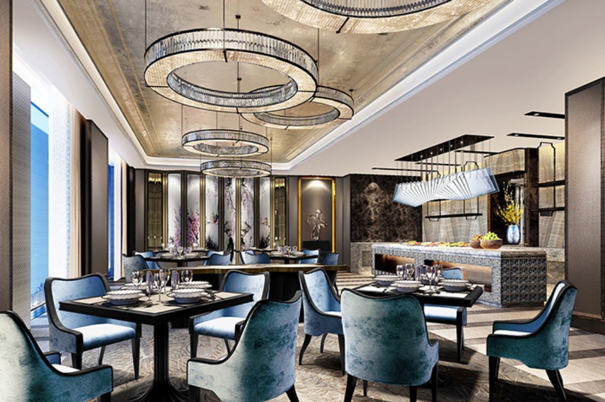 A modern dining area with a long table, blue upholstered chairs, and a chandelier.