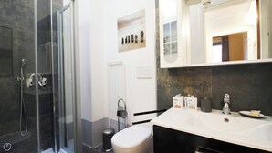 Een moderne badkamer met een douchecabine van glas, een wit wastafelmeubel en een toilet.