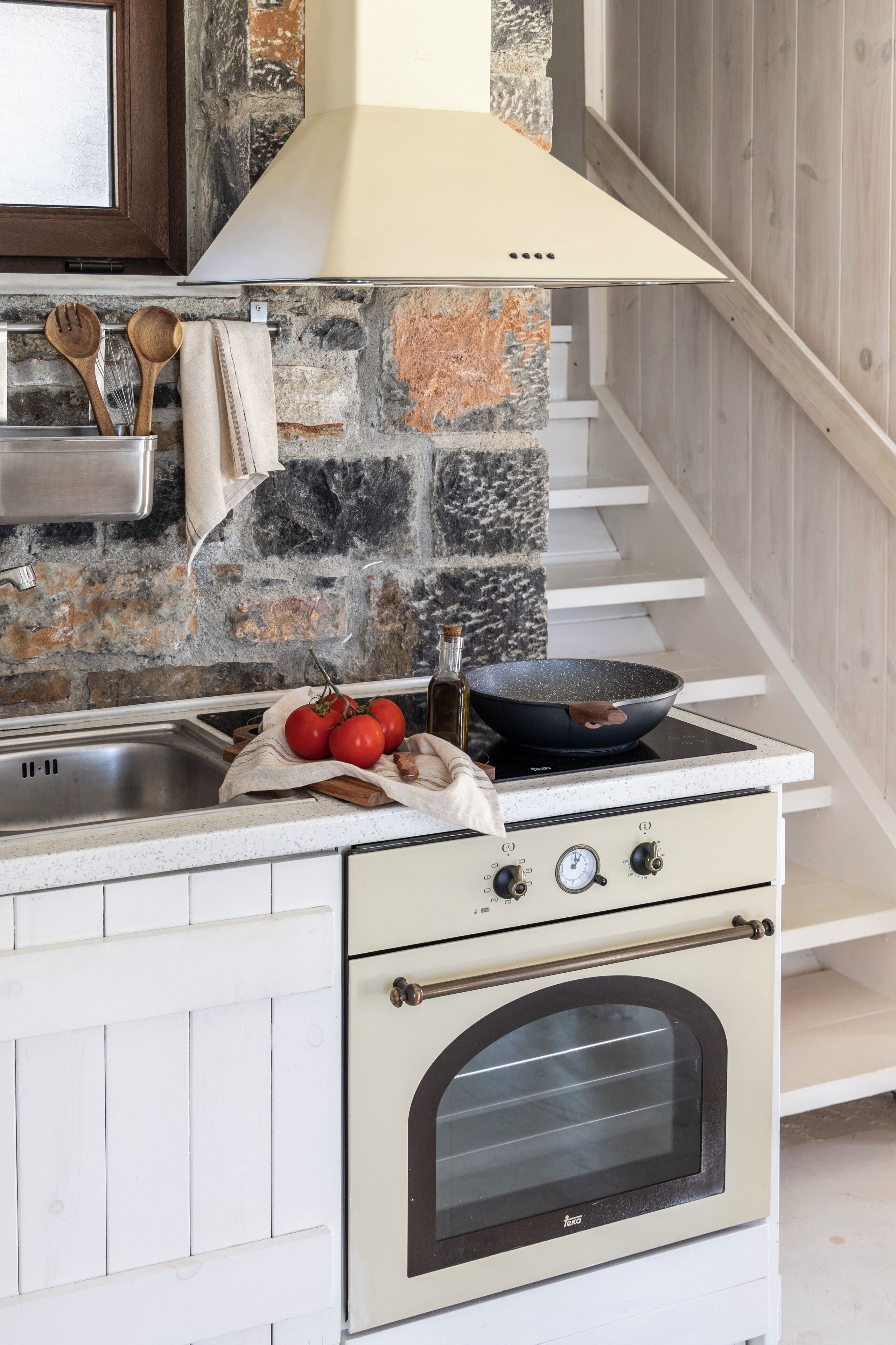 A kitchen with a stone backsplash, a stove, and a built-in oven.