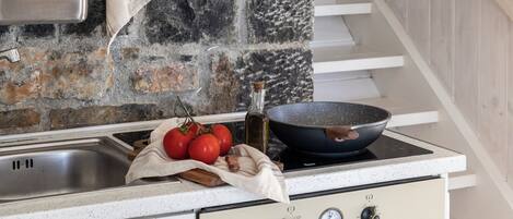 Ett kök med en väggbeklädnad av sten, en spis och en inbyggd ugn.