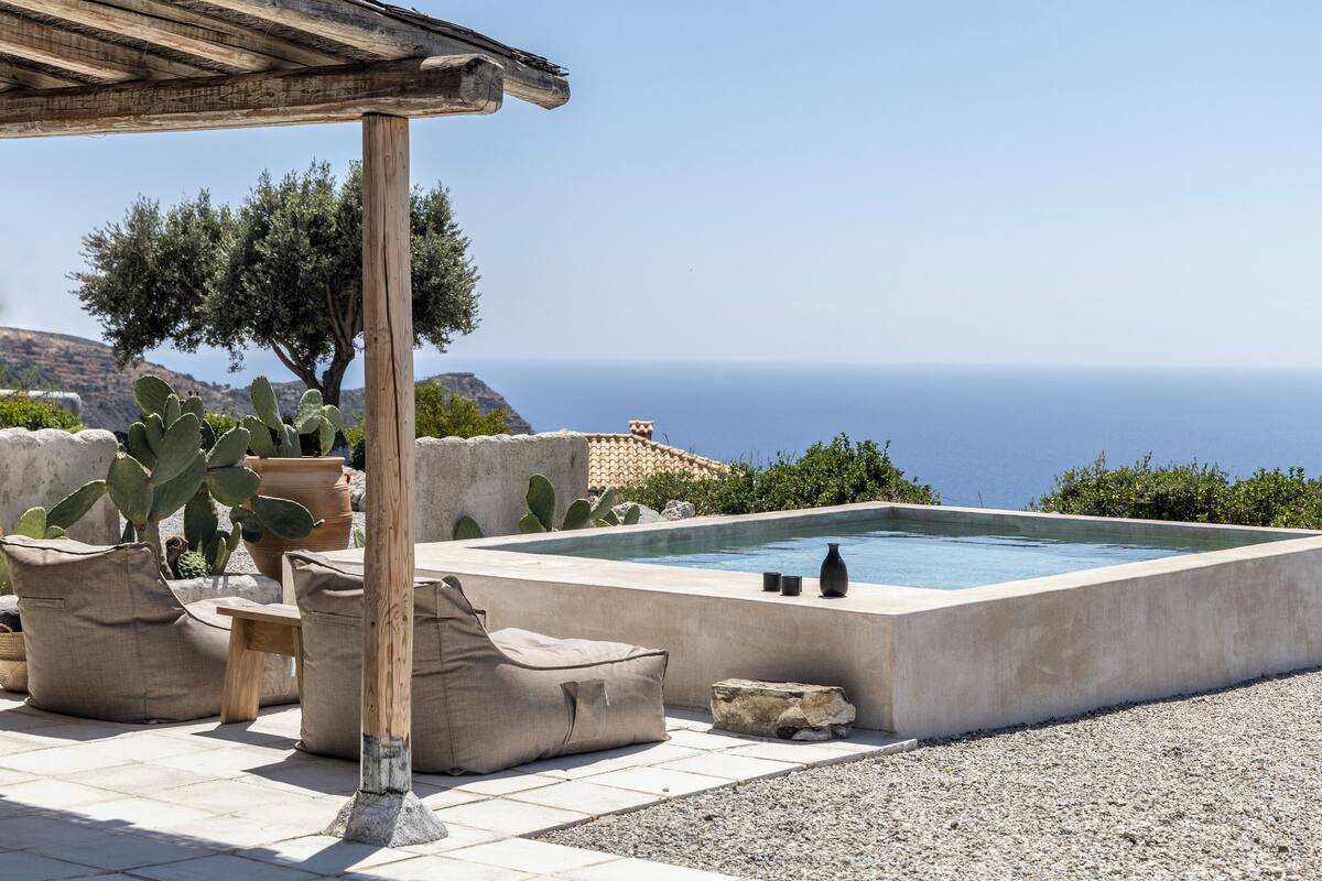 Un área de piscina con una pérgola, mobiliario exterior y cactus.