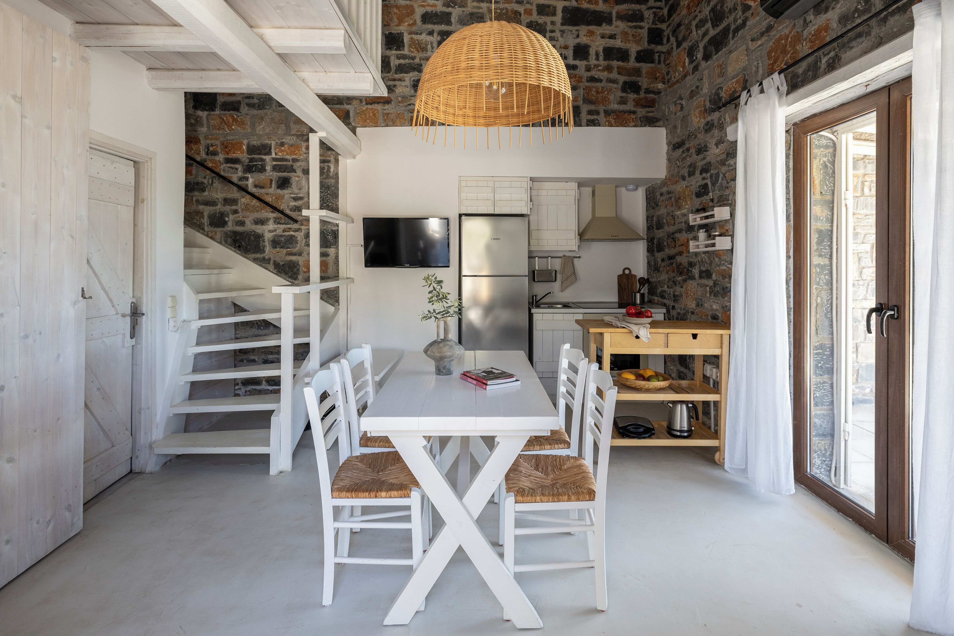 A modern kitchen with white cabinetry, a large island, and a stone wall backdrop.