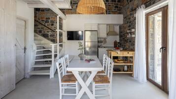 A modern kitchen with white cabinetry, a large island, and a stone wall backdrop.