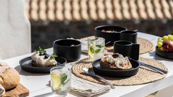 Una mesa dispuesta con comida y bebidas, incluyendo platos de comida, vasos y tazas negras.