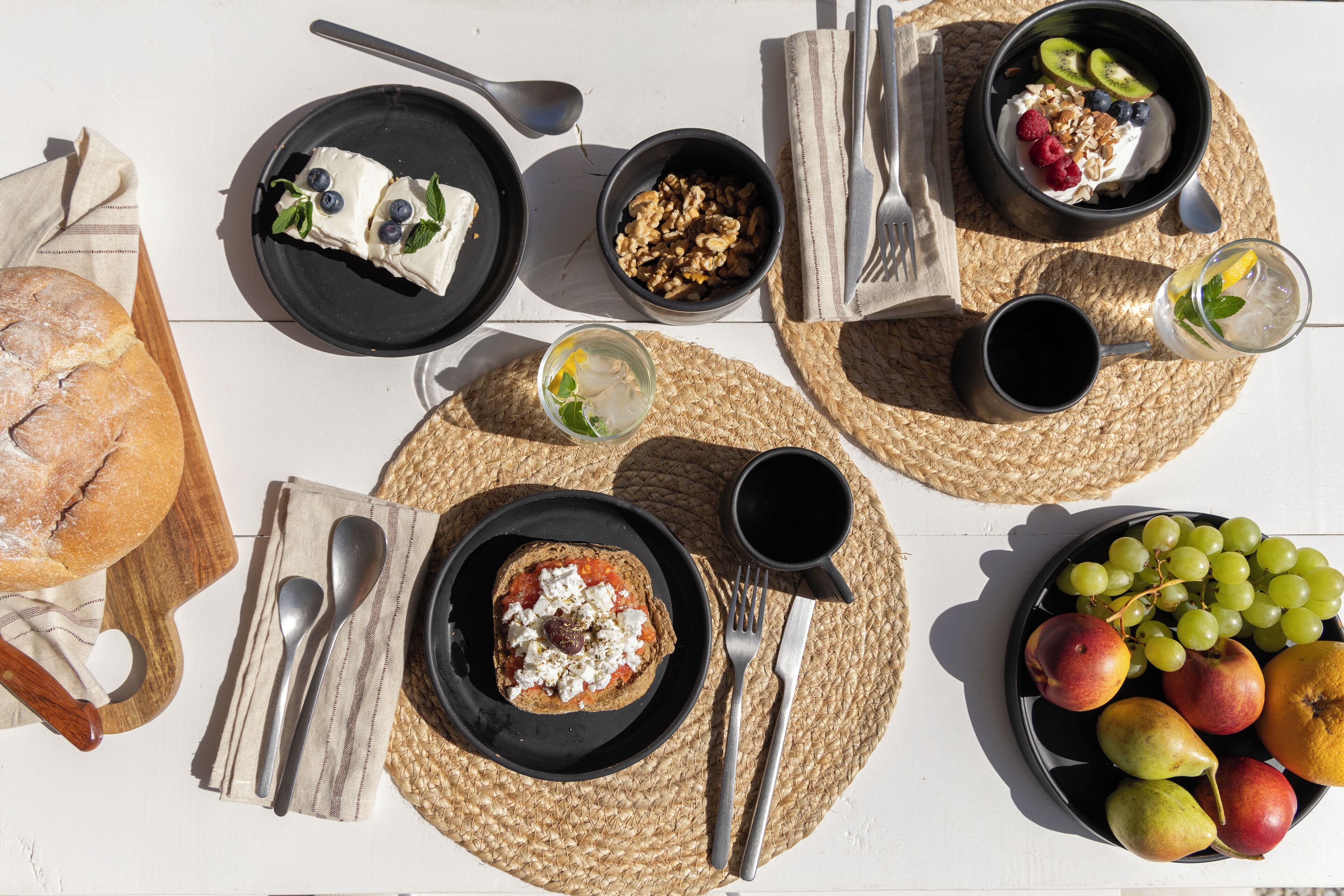 A breakfast setting with various food items and utensils on a white table.