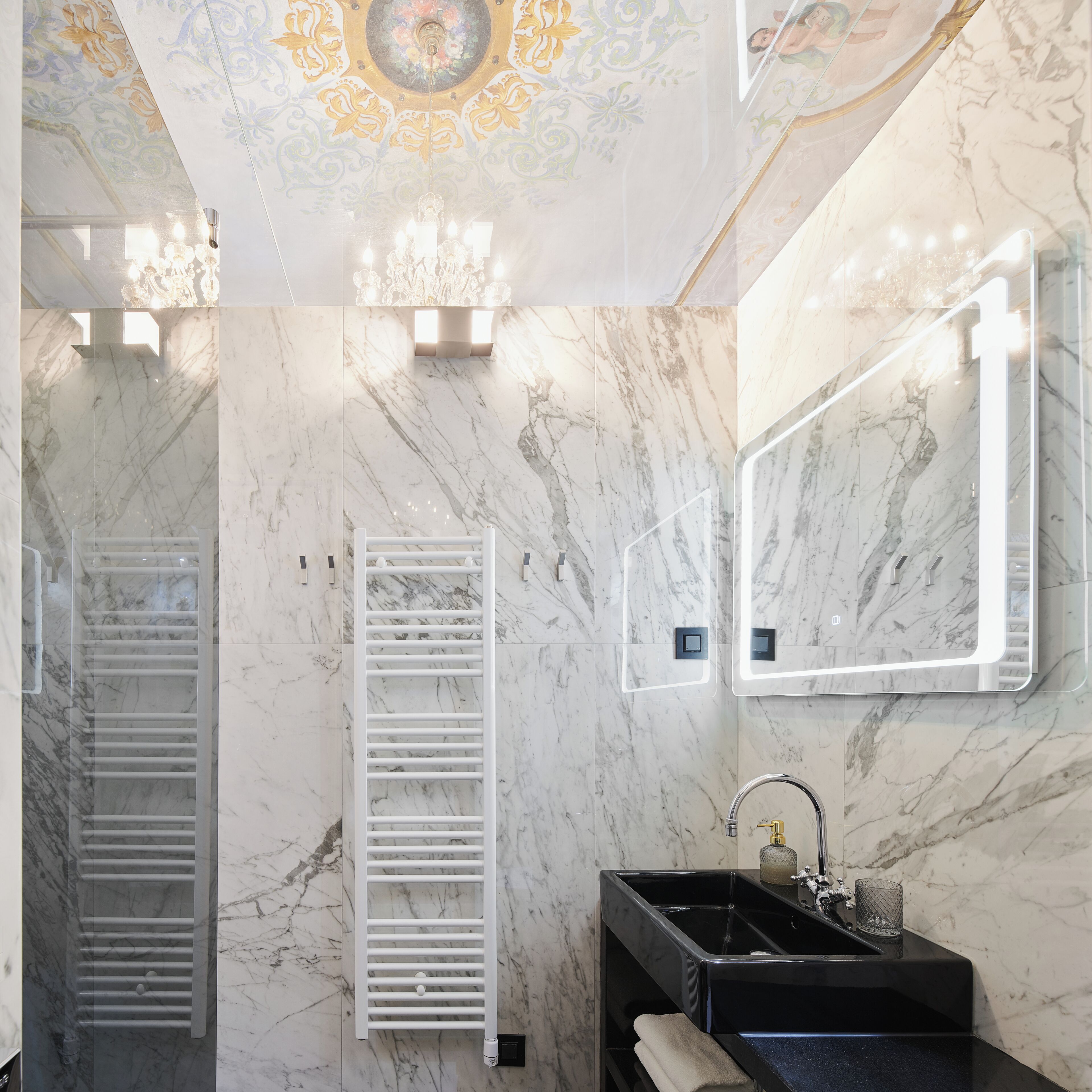 A bathroom with marble walls, a black sink, and a towel rack.