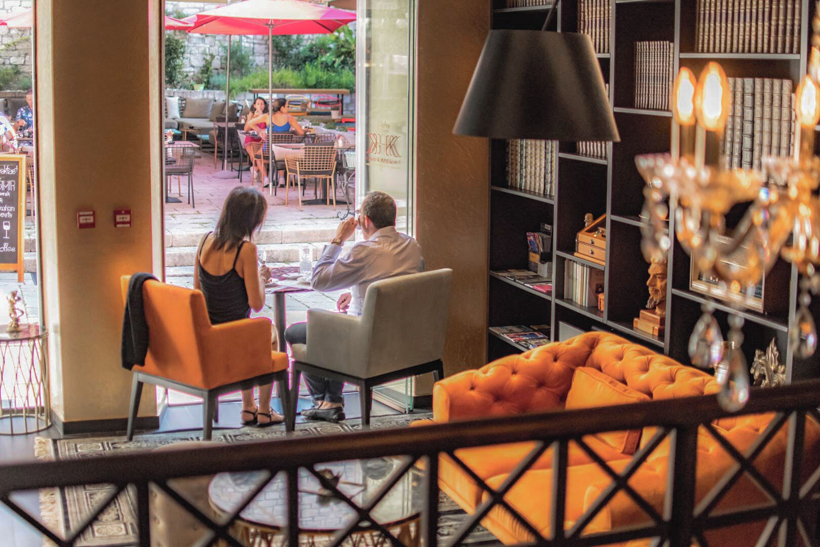 An indoor seating area with a sofa and chairs, a bookshelf, and a view of the outdoor patio area.