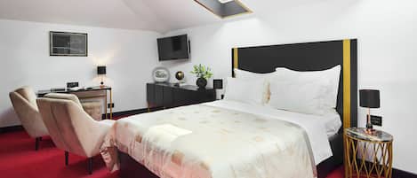 Une chambre d’hôtel avec un lit, un bureau, une chaise, une télévision et une petite table sur laquelle est posée une plante.