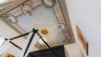 Una habitación con techos altos, decorada con frescos ornamentales y un candelabro.