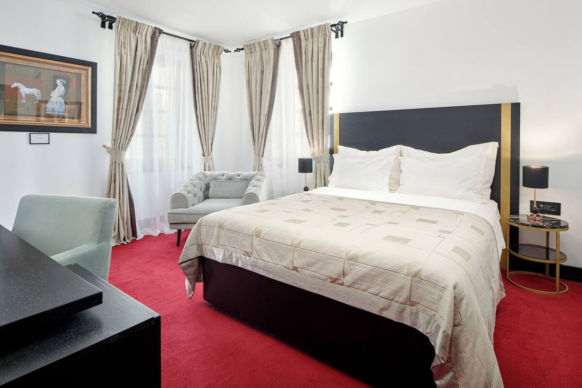 Ein Hotelzimmer mit einem großen Bett, einem Schreibtisch, einem Sessel und einem gerahmten Bild an der Wand.