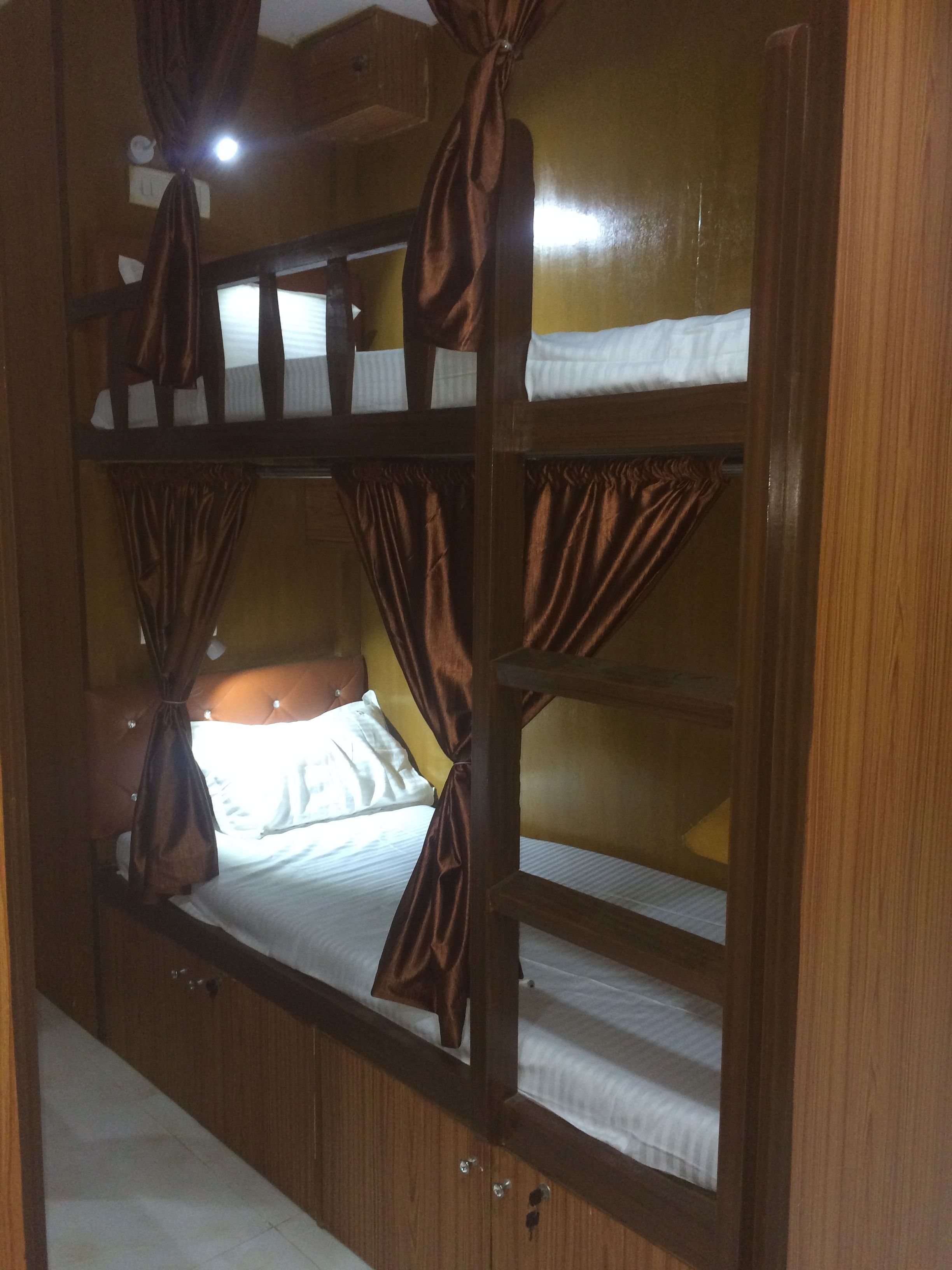 A bunk bed room with curtains and a headboard.