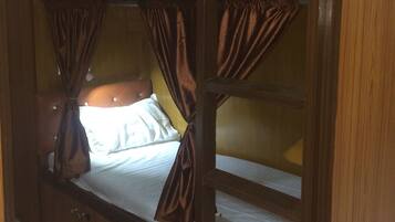 A bunk bed room with curtains and a headboard.