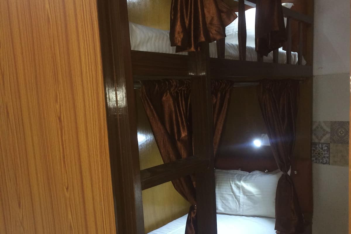 A bunk bed with curtains, a wooden door, and a tiled wall.