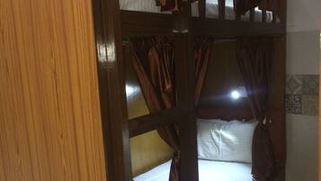 A bunk bed with curtains, a wooden door, and a tiled wall.