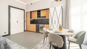 Une cuisine moderne avec des meubles en bois, un four encastré et un coin repas comprenant une table ronde et des chaises.