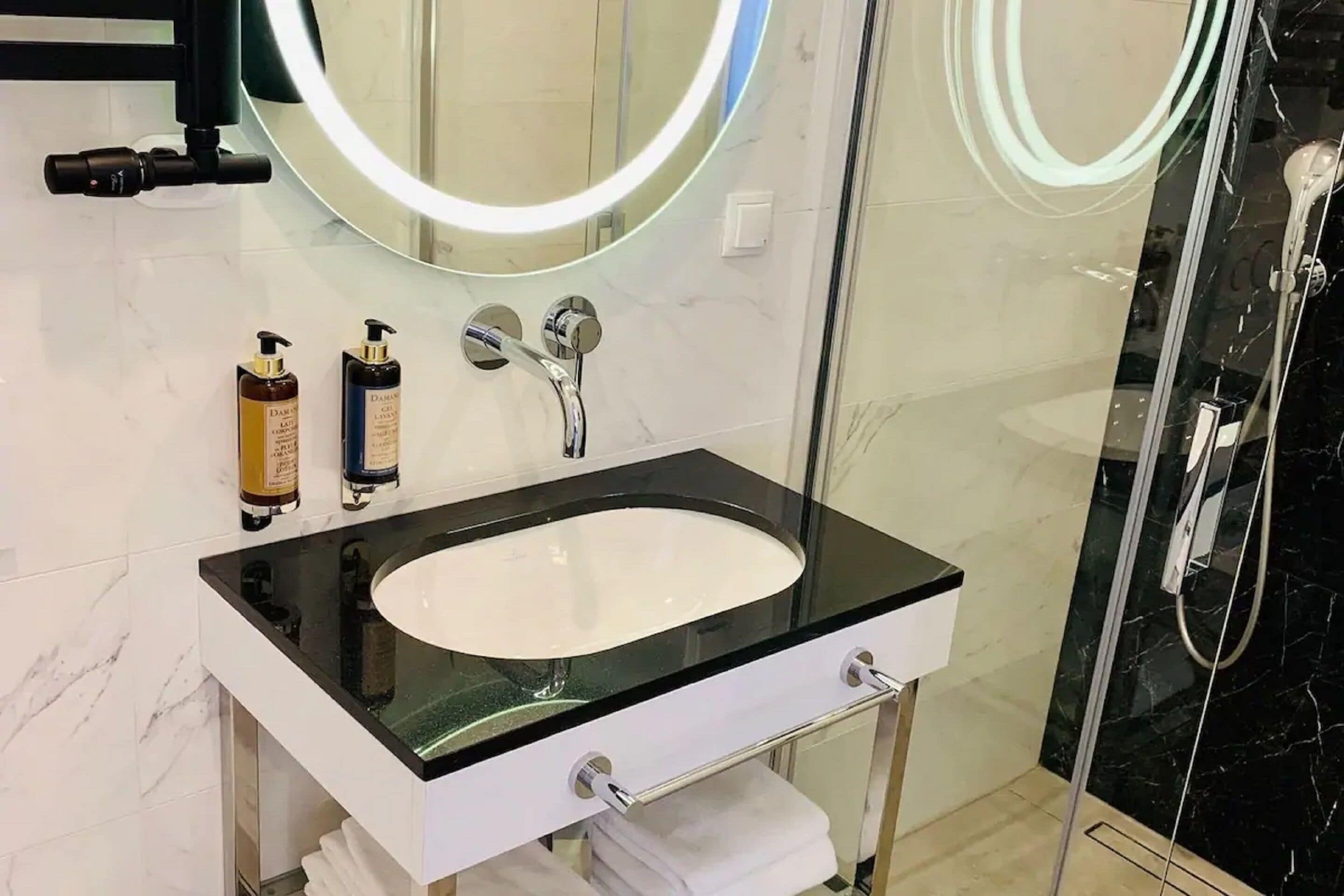 A modern bathroom with a black countertop sink, two mirrors, and a glass shower enclosure.