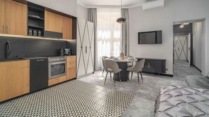 Une cuisine moderne avec des meubles en bois, un four encastré et un coin repas comprenant une table ronde et des chaises.