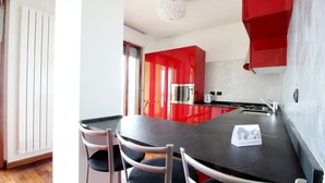 Une cuisine moderne avec des meubles de couleur rouge, un plan de travail noir et des appareils électroménagers en acier inoxydable.