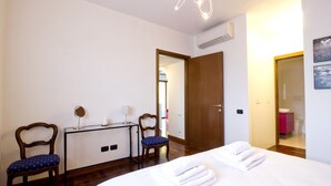 Une chambre d’hôtel avec un lit, deux chaises, un bureau et un miroir.