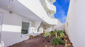 A modern white building with a sloped roof and a small garden area with various plants and rocks. - Hostal La Isla (Carboneras)