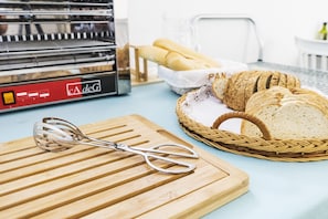 A kitchen counter with a loaf of bread, a basket of sliced bread, and a stand mixer. - Hostal La Isla (Carboneras)