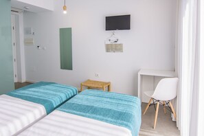 A room with two beds, a desk, a chair, a TV, and a small table. - Hostal La Isla (Carboneras)