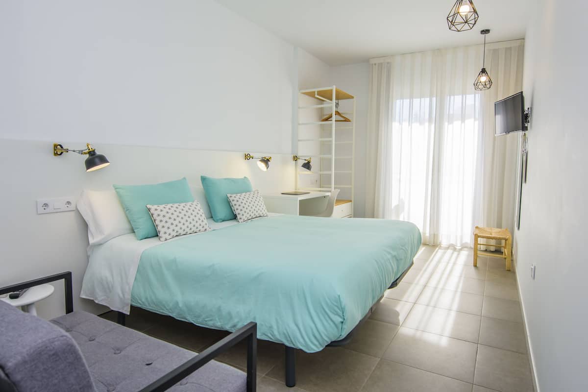 A modern bedroom with a bed, bedside tables, a desk, and a TV.
