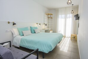 Ein modernes Schlafzimmer mit Bett, Nachttischen, Schreibtisch und Fernseher.