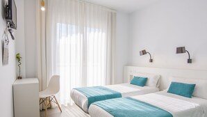 A hotel room with two beds, a desk, a chair, and a TV. - Hostal La Isla (Carboneras)