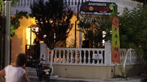 Un edificio de varios pisos con balcones, un letrero que dice 'Apartments Donsios Palms' y una palmera frente a él.