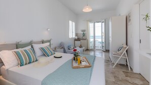 Une chambre spacieuse avec un grand lit, une table de chevet, un plateau avec des articles pour le petit-déjeuner et une vue sur le balcon.