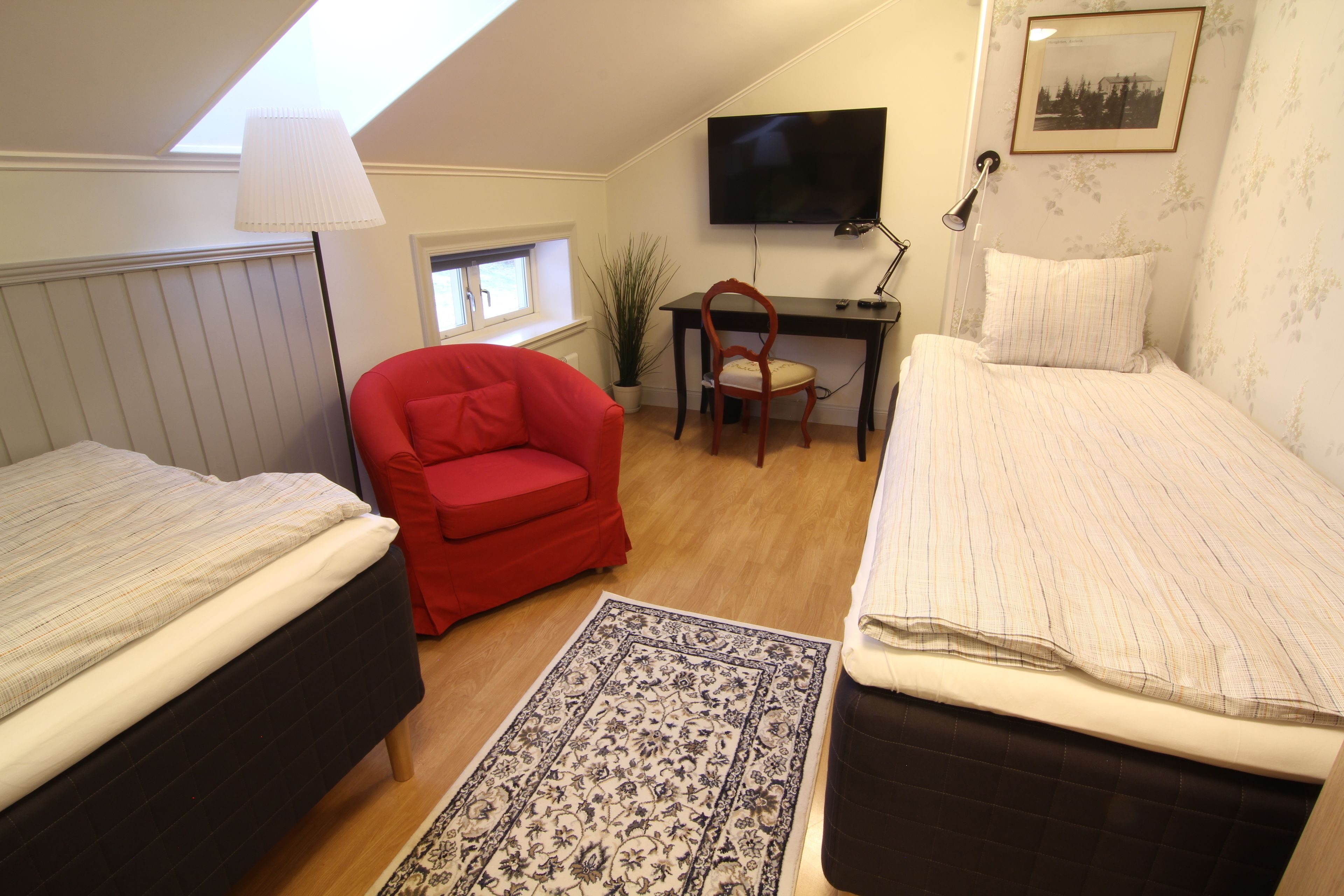 Een slaapkamer met twee bedden, een bureau, een stoel, een televisie en een raam.