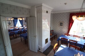 Un comedor con mesas y sillas, una chimenea y vistas a otra habitación.