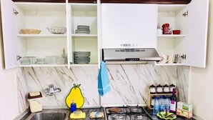 A kitchen with a gas stove, sink, and cabinets. There are various kitchen items on the counter, including bottles, a sponge, and a yellow sponge holder. - Check-in apartment Metropark Mall (Baku)