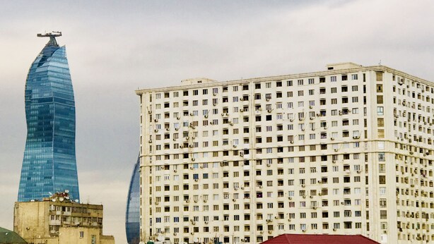 A modern skyscraper with a unique curved design and a traditional multi-story building with numerous windows. - Check-in apartment Metropark Mall (Baku)