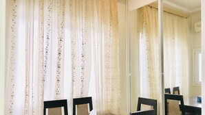 A dining area with a table and four chairs, a blue tissue box, and a mirror reflecting the room. - Check-in apartment Metropark Mall (Baku)