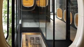 A modern interior with seating areas, a staircase, and a view through a circular window.
