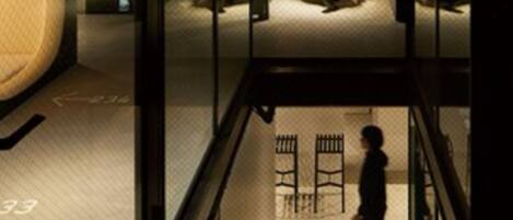 A dimly lit interior space with a person walking down a corridor. There is a sign with an arrow pointing left, and a number '33' visible on the floor.