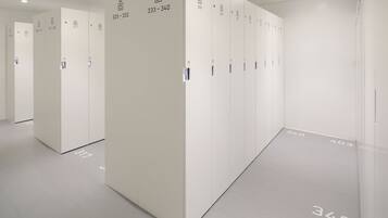 Une rangée de casiers blancs, chacun portant un numéro et des pictogrammes indiquant les équipements disponibles.