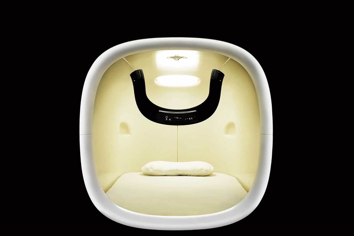Habitación moderna y minimalista con pared blanca curva, una lámpara central y una única almohada blanca en el suelo.