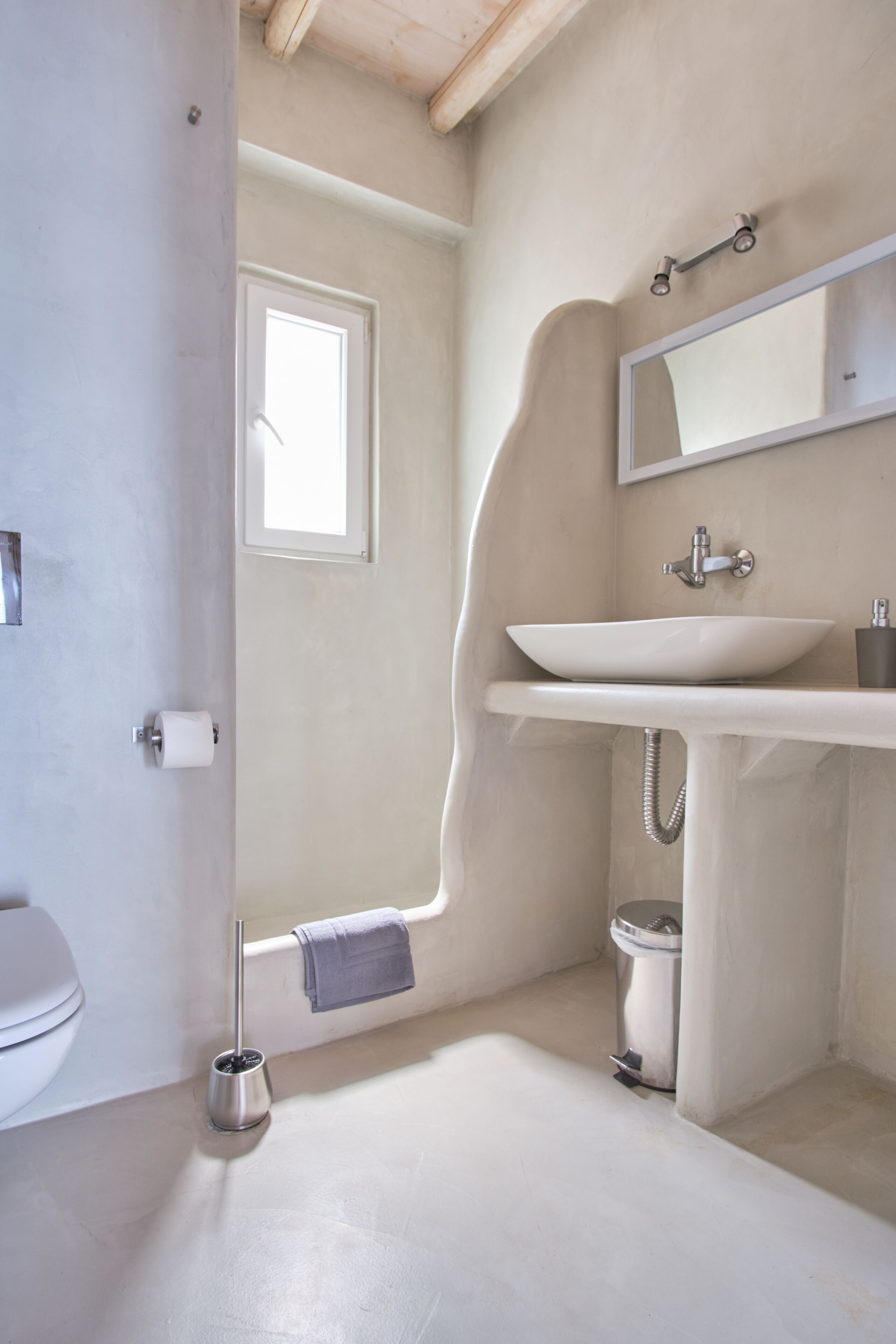 Un baño con lavamanos blanco, un espejo, inodoro y zona de ducha.